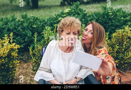 Mädchen nimmt Selfie mit ihrer Mutter im Rollstuhl Stockfoto