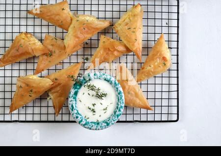 Griechische Küche. Tiropita, griechische Feta-Käse-Dreieck-Kuchen auf weißem Hintergrund. Draufsicht. Stockfoto