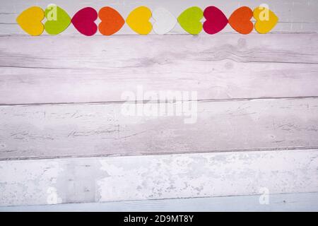 Bunte Filz Herzen auf dem Hintergrund der alten hölzernen Planken ähnelt einem alten Parkettboden. Konzept der Valentinstag und die Liebe im Allgemeinen. Stockfoto