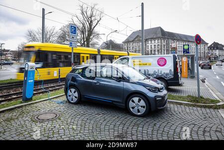 Elektroauto steht an der Mobilstation Landgericht an einer Ladestation, hinter einer Straßenbahn, Essen, Ruhrgebiet, Nordrhein-Westfalen, Deutschland Stockfoto