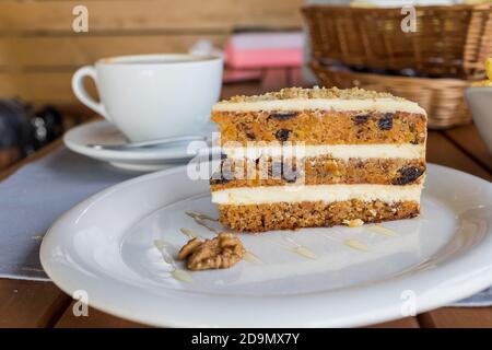 Karotten und Kürbiskuchen mit Kaffeesahne in einem Schnitt Auf dem Teller.Delicious in Scheiben geschnittenen Karottenkuchen.Tasse Cappuccino und Slice Von Kuchen auf einer weißen Untertasse Stockfoto