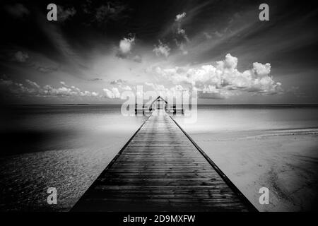 Schwarz-weiße Strandszene. Starke kontrastierte getönte Foto. Dramatische Strandlandschaft mit über Wasser Villa Bungalow auf den Malediven. Künstlerische Landschaft Stockfoto