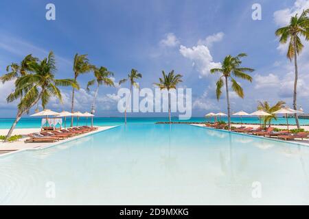 Sommer Reise Tourismus Luxus Landschaft. Luxuriöses Strandresort mit Swimmingpool und Strandliegen oder Liegen Sonnenschirme mit Palmen und blauem Himmel Stockfoto