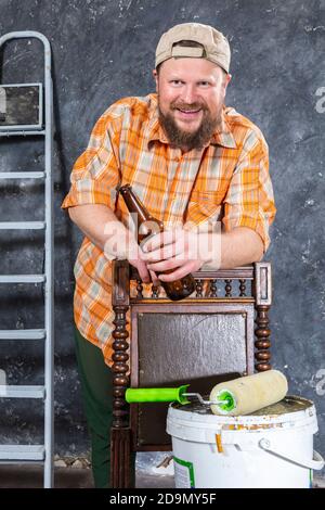 Fröhlicher bärtiger Vorarbeiter hat eine Pause mit einer Flasche Bier studio-Porträt Stockfoto