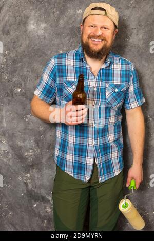 Fröhlicher bärtiger Vorarbeiter hat eine Pause mit einer Flasche Bier studio-Porträt Stockfoto