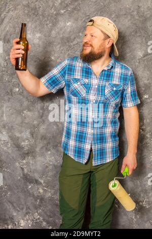 Fröhlicher bärtiger Vorarbeiter hat eine Pause mit einer Flasche Bier studio-Porträt Stockfoto