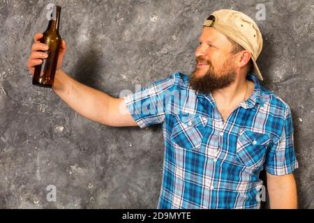 Fröhlicher bärtiger Vorarbeiter hat eine Pause mit einer Flasche Bier studio-Porträt Stockfoto