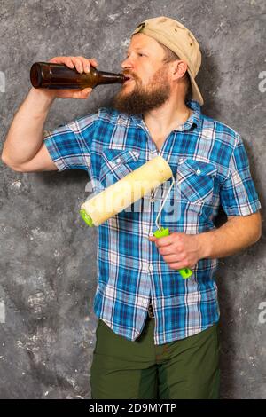 Fröhlicher bärtiger Vorarbeiter hat eine Pause mit einer Flasche Bier studio-Porträt Stockfoto