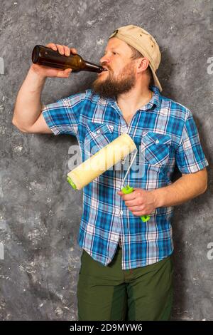 Fröhlicher bärtiger Vorarbeiter hat eine Pause mit einer Flasche Bier studio-Porträt Stockfoto