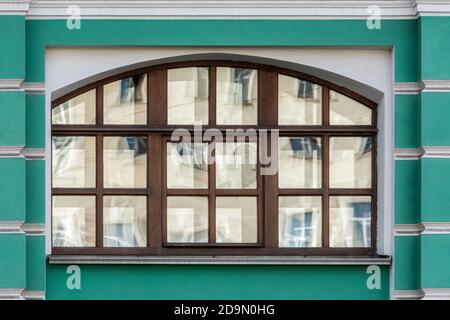 Architektonische Gestaltung eines gewölbten Fensters gegen eine grüne Wand. Aus der Serie Windows of Saint Petersburg. Stockfoto