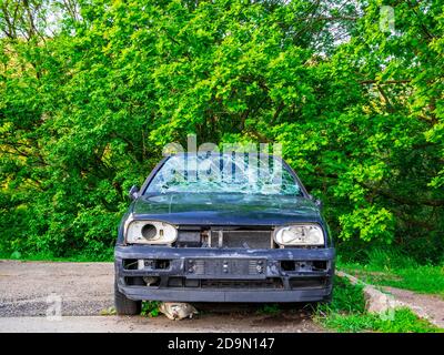 Ein verlassenes Autowrack am Rande des Parkplatzes Stockfoto