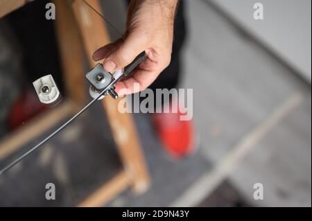 Nahaufnahme des Duschkabinen-Trolleys während der Installation an der Glastür. Die Hand des kaukasischen Mannes hält es in seinem Sitz. Stockfoto