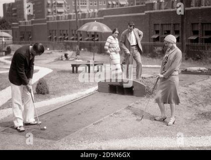 1920ER-1930ER-GRUPPE ZWEI PAARE SPIELEN MINIGOLF PHILADELPHIA PA USA - G4147 HAR001 HARS ALTEN MODE-STIL FREUND JUNG ERWACHSENE WETTBEWERB LIFESTYLE FRAUEN VERHEIRATET EHEGATTEN EHEMÄNNER VEREINIGTE STAATEN KOPIE RAUM FREUNDSCHAFT IN VOLLER LÄNGE DAMEN PERSONEN VEREINIGTE STAATEN VON AMERIKA MÄNNER GOLF UNTERHALTUNG B&W PARTNER NORDAMERIKA DATING MINIATUR NORDAMERIKA FREIZEIT GOLFER FREIZEIT STILE PA ERHOLUNG ATTRAKTION GOLF BALL COURTSHIP KONZEPTIONELLE FREUNDLICHE LINKS STILVOLLE MÖGLICHKEIT MODEN SOZIALE AKTIVITÄT ZWEISAMKEIT EHEFRAUEN JUNGE ERWACHSENE MANN JUNGE ERWACHSENE FRAU SCHWARZ UND WEISS KAUKASISCH ETHNISCHE ZUGEHÖRIGKEIT Stockfoto