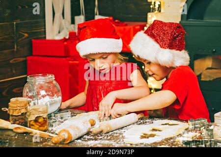 Frohe Weihnachten. Weihnachtliche Speisen und Getränke. Weihnachtsmann Kinder machen Cookie. Lustige Kinder bereiten den Teig vor, der mit Mehl in der Küche spielt. Stockfoto