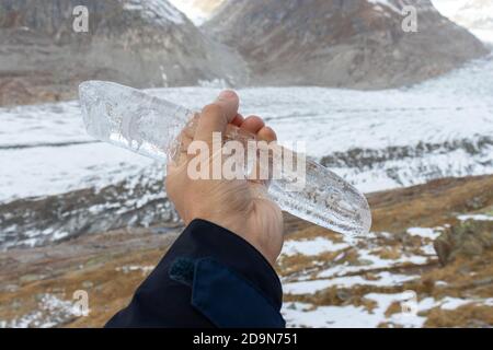 Nahaufnahme des Eiszapfes vor Gletscher- und Berglandschaft am aletschgletscher. Bewegung gegen den Klimawandel. Stockfoto