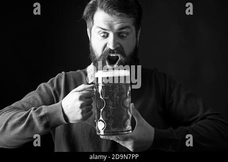 Emotional lustig bärtig betrunken Hipster hält Handwerk Flaschenbier. Fröhlicher Brauer. Bärtiger Mann mit einem Glas Bier. Stockfoto