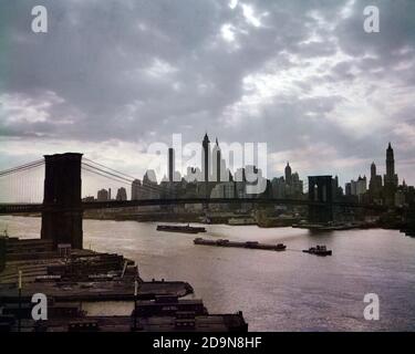 DIE SKYLINE VON MANHATTAN IN DEN 1950ER JAHREN MIT BROOKLYN BRIDGE SCHLEPFT FRÜH MORGENANSICHT ÜBER EAST RIVER NEW YORK CITY USA - KR964 HAR001 HARS NYC REAL ESTATE CONNECTION NEW YORK STRUCTURES STÄDTE GEBÄUDE NEW YORK CITY PANORAMA SPANNWEITE SCHLEPPER BARGES BRÜCKEN HAR001 VERBINDEN SIE ALTMODISCHE WOLKENKRATZER Stockfoto