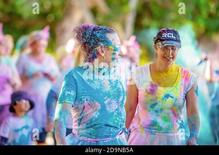 MACKAY, QUEENSLAND, AUSTRALIEN - JUNI 2019: Unbekannte Frauen, die mit farbigem Pulver bedeckt sind, nehmen am Color Frenzy Fun Run Teil Stockfoto