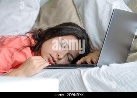 Das Mädchen schlief während der Arbeit auf einem Laptop ein. Schlaf während der Arbeitszeit. Probleme mit Freiberuflern. Stockfoto