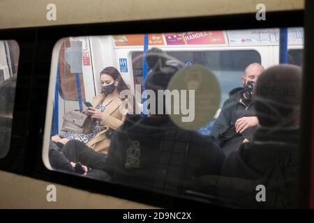 Pendler in der Londoner U-Bahn tragen Gesichtsmasken während der zweiten Lockdown, London, England Stockfoto