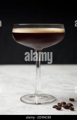 Vorderansicht eines Espresso Martini auf einem Marmortisch. Kaffeebohnen-Dekoration Stockfoto