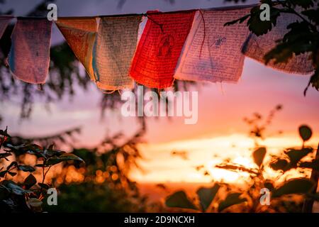 nepalesische Gebetsfahnen winken während des Sonnenuntergangs Stockfoto