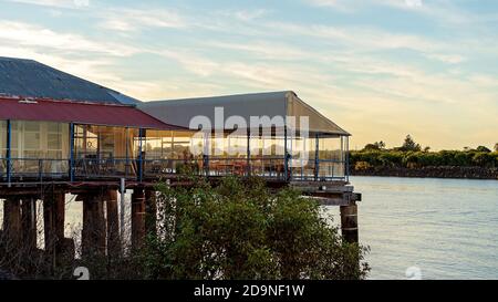 Mackay, Queensland, Australien - 12. Juli 2019: Menschen, die bei Sonnenuntergang im australischen Restaurant am Wasser am Fluss speisen Stockfoto