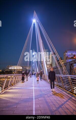 Fußgänger gehen auf einer weißen Brücke über der Themse Nachts Stockfoto