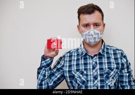 Mann im karierten Hemd zeigen Isle of man Flagge Karte in der Hand, tragen Schutzmaske isoliert auf weißem Hintergrund. Europa Länder Coronavirus Konzept. Stockfoto