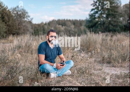 Stylischer brutaler Mann dampft und gibt eine Wolke aus Dampf frei. Verdampfung. Stockfoto