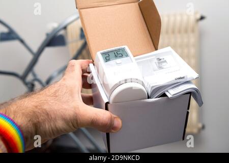 Paris, Frankreich - Oct 25, 2020: POV männliche Hand zeigt ausgepackt Paket von Vaillant Ambisense VR50 Thermostat-Ventil angeschlossen IoT-Gerät an den Gas-Heizungspumpe Kessel Stockfoto