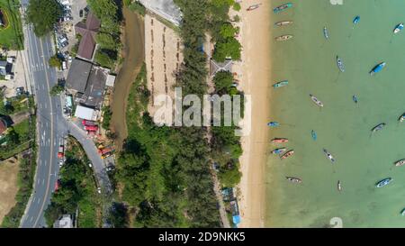 Luftdrohne Foto aus der Vogelperspektive von oben auf Asphalt Straße in der Nähe des Meeres mit langen Schwanz Fischerboote an phuket thailand Stockfoto