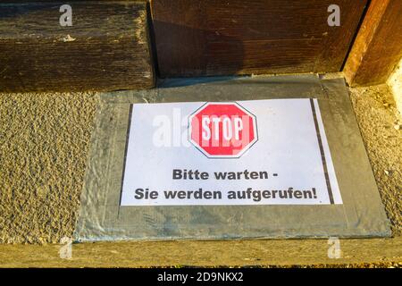 Hinweisschild zum Schutz vor Coronavirus vor der Ladentür, Stop Please wait heißt, München, Oberbayern, Bayern, Deutschland Stockfoto