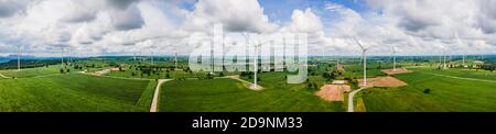Panorama von vielen Windmühlen auf dem weiten Grasland mit Bergen und Himmel als Hintergrund in Thailand. Stockfoto