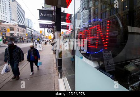 Toronto, Kanada. November 2020. Menschen mit Gesichtsmasken gehen am 6. November 2020 an einem "offenen" Schild eines Restaurants in Toronto, Kanada, vorbei. Kanadas Arbeitslosenquote fiel auf 8.9 Prozent im Oktober von September neun Prozent, nach Statistik Kanada am Freitag. Quelle: Zou Zheng/Xinhua/Alamy Live News Stockfoto