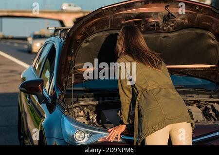 Junge Frau mit kaputten Auto auf der Autobahn Straßenrand. Stockfoto