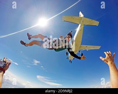 Lustige Fallschirmspringer springt aus einem Flugzeug an einem Sommertag. Standpunkt Stockfoto