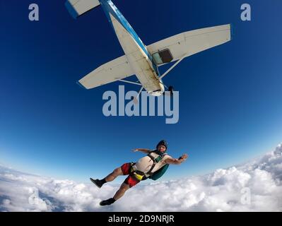 Lustige Fallschirmspringer springt aus einem Flugzeug an einem Sommertag. Standpunkt Stockfoto