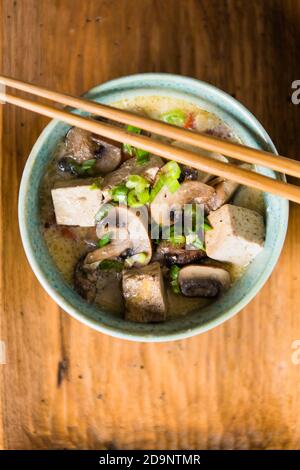 Tofu und Pilzsuppe in blauer Schüssel mit Essstäbchen in der Nähe Stockfoto