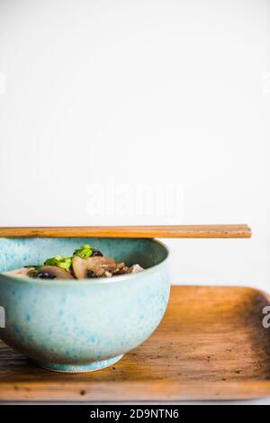 Tofu und Pilzsuppe in blauer Schüssel mit Essstäbchen in der Nähe Stockfoto