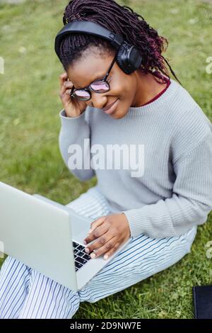 Afroamerikanischer Student mit Laptop und Musik auf der Straße hören Stockfoto