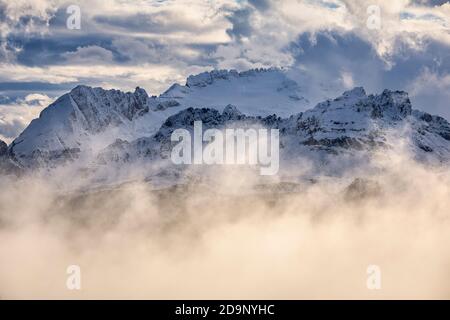 Der scharfe Grat von Padon und hinter der Marmolada umgeben von Wolken in einer Winterlandschaft, Dolomiten, Provinz Belluno, Venetien, Italien, Europa Stockfoto