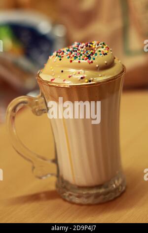 Dalgona Kaffee in Glas Becher mit Regenbogen bestreut Stockfoto
