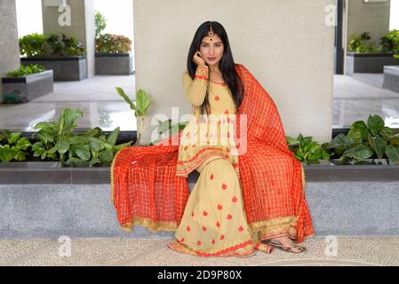 Junge Frau trägt traditionelle indische Kleidung während des Sitzens Stockfoto