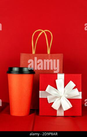 Frohes neues Jahr 2021 weihnachtseinkäufe. Geschenkbox, Basteltasche aus Papier und Kaffeetasse auf rotem Hintergrund, Monochrom. Stockfoto
