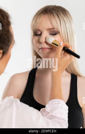 Die Make-up Dame bei der Arbeit. Geschlossene Augen mit Lidschatten. Zarter, sehr feiner Teint. Stockfoto