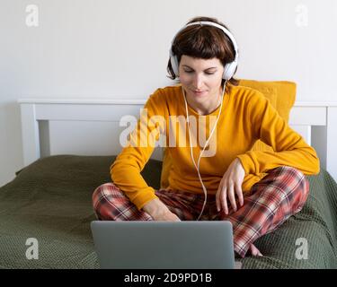 Ältere Frau sitzt auf dem Bett im Schlafzimmer und tippen auf Laptop. Stockfoto