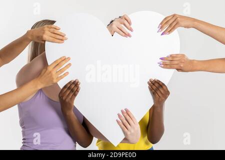 Herzform durch weibliche Hände gehalten. Viele Frauen aus verschiedenen Ländern haben ein gemeinsames Herz in einer Geste der Einheit. Stockfoto