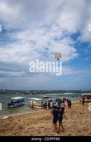 Eine Weitwinkelaufnahme am Pandawa Beach, Bali mit Sonnenschirmen am Sandstrand mit starken Wellen am Meer und einem blauen Himmel Stockfoto