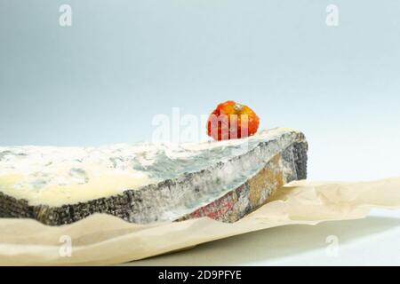 Mehrere Stücke verwöhnter Käse mit verwöhnter Kirschtomate auf blauem Hintergrund. Konzept für Lebensmittelabfälle. Nahaufnahme. Horizontale Ausrichtung. Speicherplatz kopieren. Stockfoto